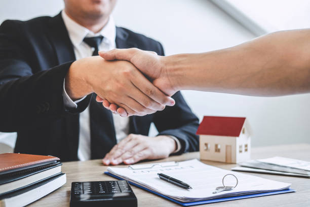 istock Midsection Of Agent Giving Handshake To Customer In Office 1155471201