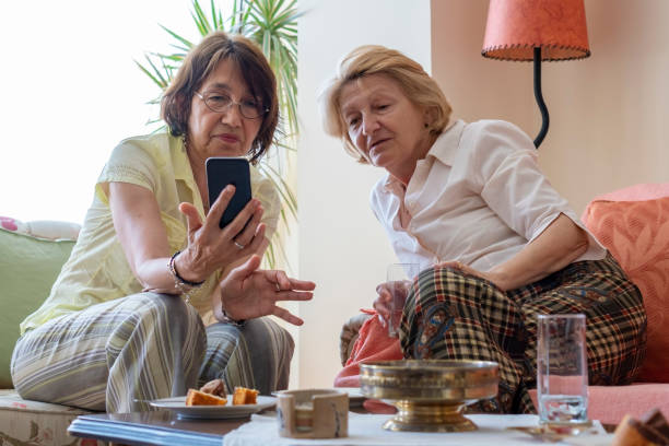 istock Two senior women  talking and using a mobile at home 1155471647
