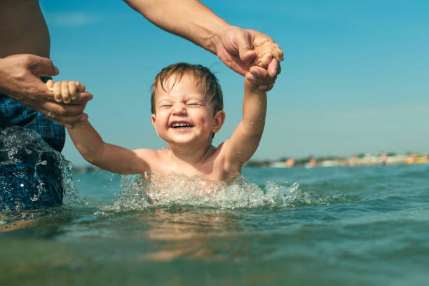 istock Happy boy with father in the sea on beach vacations 1155480201