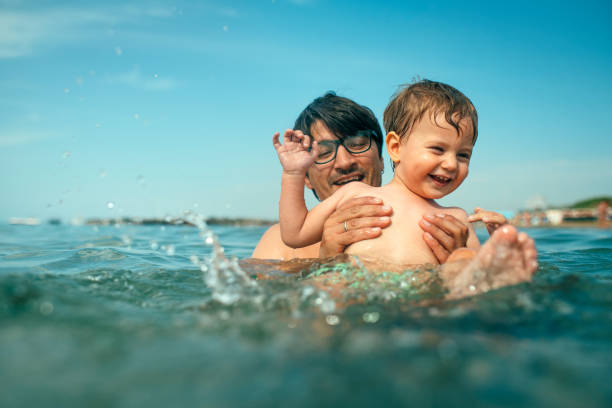 Happy boy with father in the sea on beach vacations Child having fun in the sea on summer holidays family beach vacations travel stock pictures, royalty-free photos & images