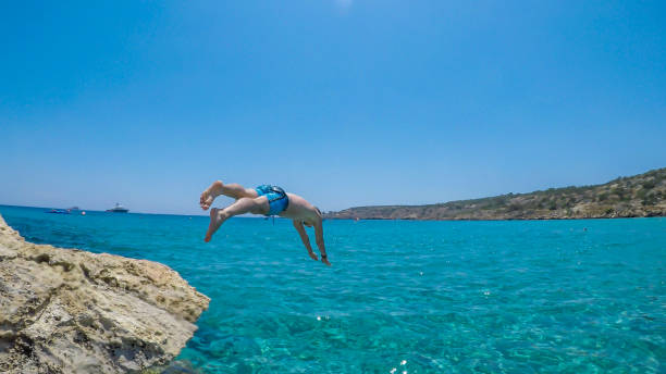 istock Cyprus - A man jumping into the sea from a rock 1155481449