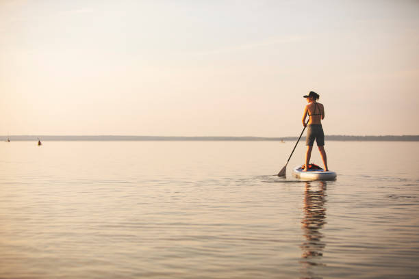 istock Young adult woman paddle boarding 1155481458