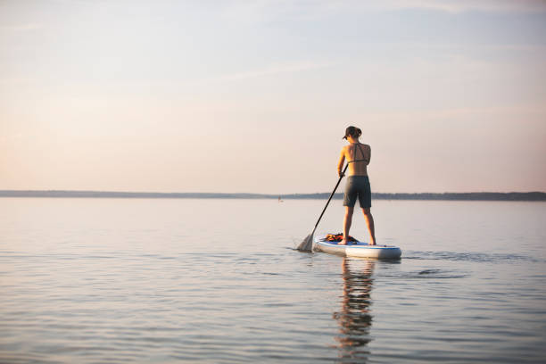 istock Young adult woman paddle boarding 1155483856