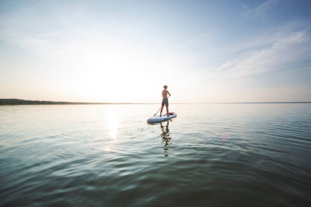istock Young adult woman paddle boarding 1155483989