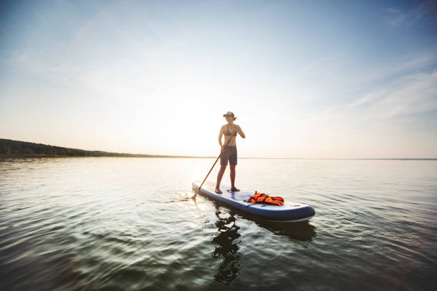 istock Young adult woman paddle boarding 1155484107