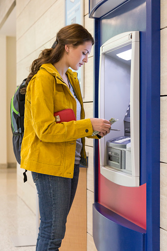 Young woman college university student getting cash money at ATM. Personal banking finance concept.