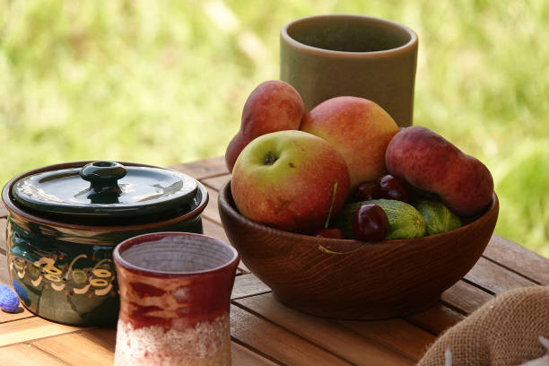 istock Fruit bowl and clay cups on outdoor table 1155484735