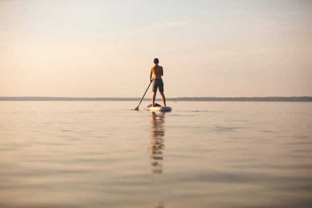 istock Young adult woman paddle boarding 1155485949