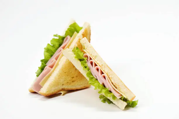 Photo of Two triangular sandwiches with cheese and ham. The sandwich is made from slices of fried white bread.  White background.