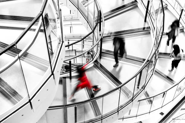 blurred motion of people running down futuristic modern spiral staircase - office time lapse imagens e fotografias de stock