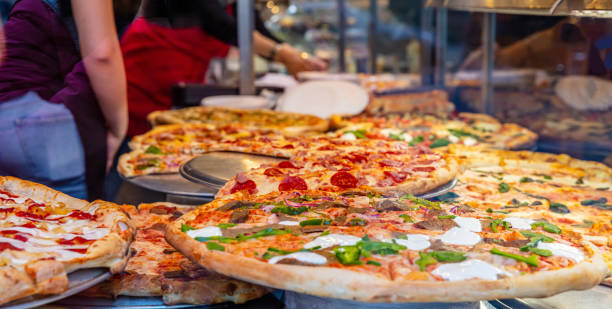 상점 디스플레이에서 이탈리아 피자의 구색. 피자를 제공 하는 여성 노동자. - pizzeria 뉴스 사진 이미지