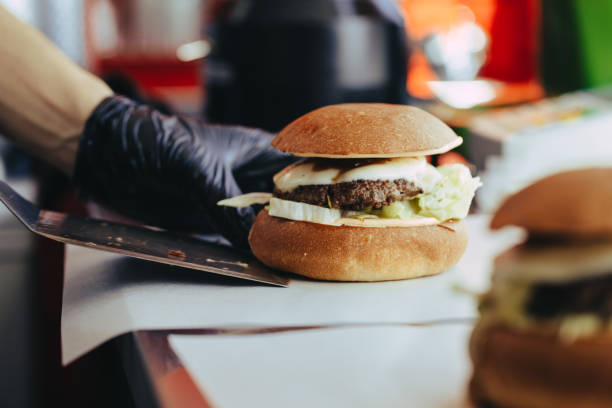 istock Cook preparing burger adding the sauce on the cream cheese. Three burgers. 1155488114