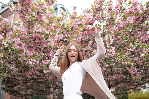 beautiful young happy woman in a blouse and glasses near the cherry blossoms. flowers