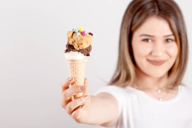 istock beautiful woman eating ice cream 1155497903