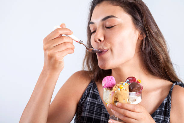 istock beautiful woman eating ice cream 1155498965