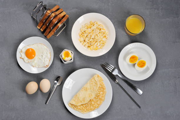 istock Different dishes from chicken eggs. Omelette, soft-boiled, hard-boiled, fried, scrambled eggs. In the frame, toasts and a glass of juice. Close-up. View from above. 1155498997
