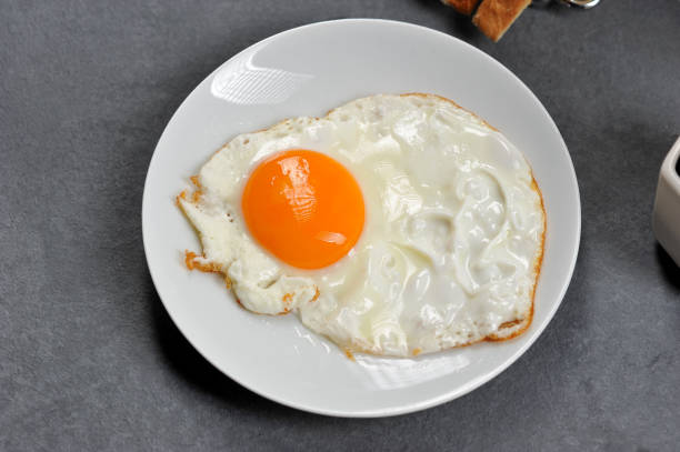 istock Fried egg glasunya on a white plate. Gray background. View from above. 1155499014