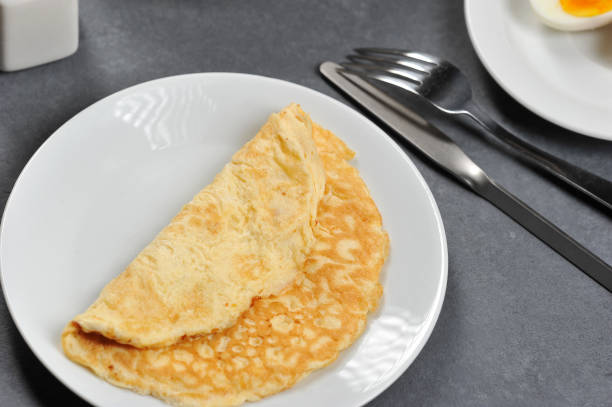 istock Omelette from chicken eggs on a white plate. Next to the plate are cutlery. 1155499021