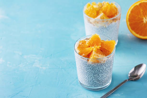 ヨーグルトとチア種子健康的なビーガンスーパーフード.シンプルな栄養価の朝食。甘い乳製品プディングのデザートに柑橘系のフルーツを添えます。オレンジとスプーンの半分がテーブルに - tablespoon chia healthy eating seed ストックフォトと画像