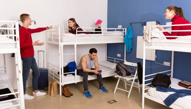 istock Young men and women friendly interacting while staying in modern comfy hostel 1155505477