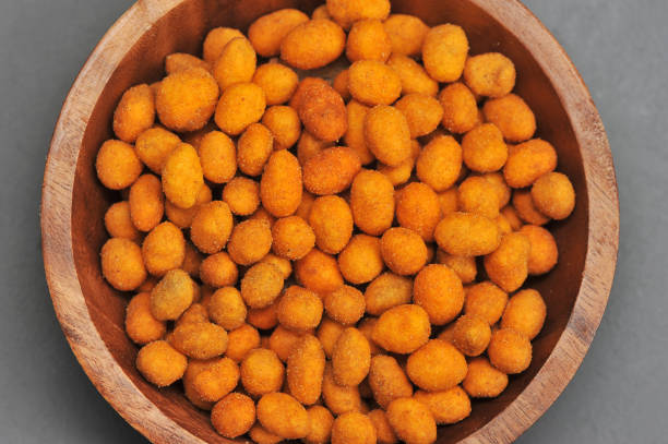 Peanuts in a crispy crust in a wooden bowl. Gray background. View from above. Close-up. Macro photography.
