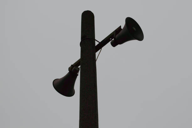 istock Two loudspeakers on a pole on a gray background. 1155509721