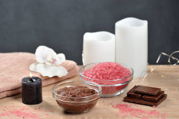 set for spa treatments. chocolate body scrub, chocolate bath salt, towel. the composition is complemented by candles, an orchid flower and pieces of dark chocolate. - chocolate spa treatment alternative therapy towel imagens e fotografias de stock