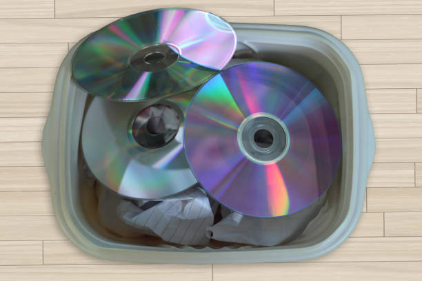 przestarzała koncepcja: cd, dvd w koszu są odrzucane. ewolucja technologiczna. odpady elektroniczne na tle czarnego drewna. - recycling symbol audio zdjęcia i obrazy z banku zdjęć