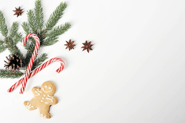 istock Christmas composition. The composition includes ginger cookies in the form of a little man, caramel cane, spruce twig, pine cone, anise. White background. Space under the text. 1155514201