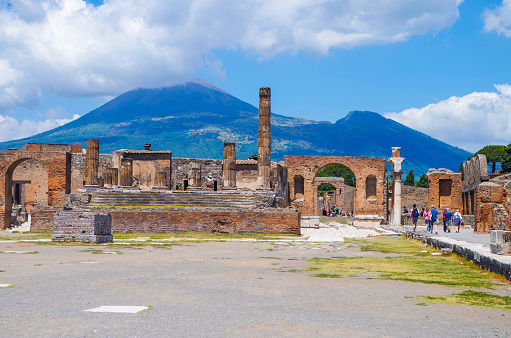 Pompeii, archeological site: Ancient ruins of the Temple of Jupiter, with view on smoking Mount Vesuvius.