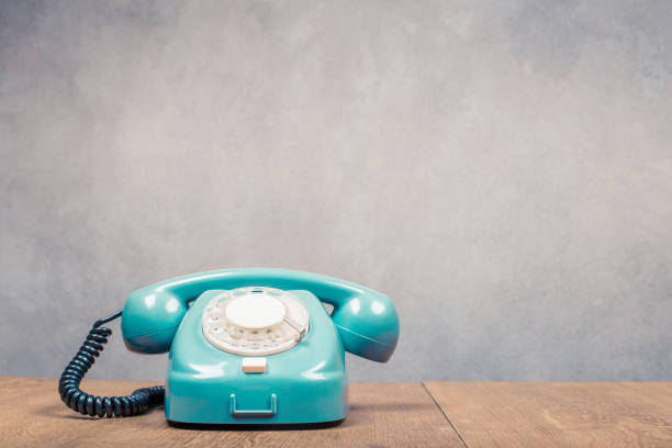 Retro old mint green telephone from 60s on table front textured concrete wall background. Vintage style filtered photo stock photo
