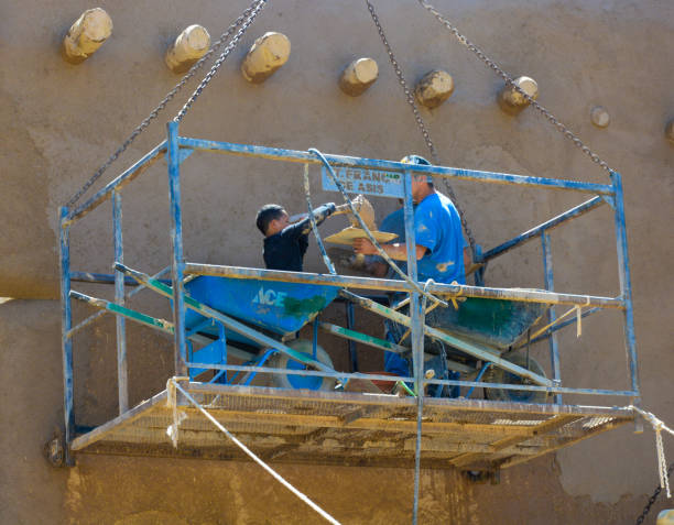 volunteers applying adobe (mud) to a church wall - ranchos de taos imagens e fotografias de stock