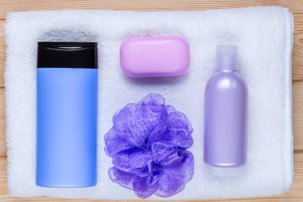 Front view of various shower products such as a shampoo, a pumice stone, a towel, a bath sponge and a bar of soap isolated on white background.