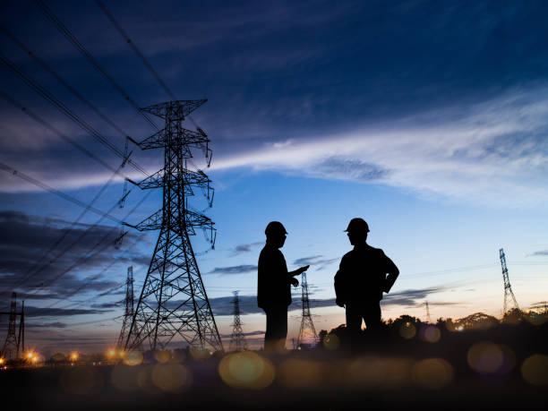 istock Silhouette Successful male engineer standing survey work on construction over blurred high-voltage pylons and construction. examination, inspection, survey 1155534212