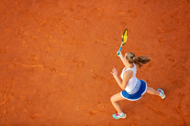 tiro aéreo de um jogador de ténis fêmea em uma corte durante o fósforo. mulher nova que joga o tênis. opinião de ângulo elevado. - tennis forehand people sports and fitness - fotografias e filmes do acervo