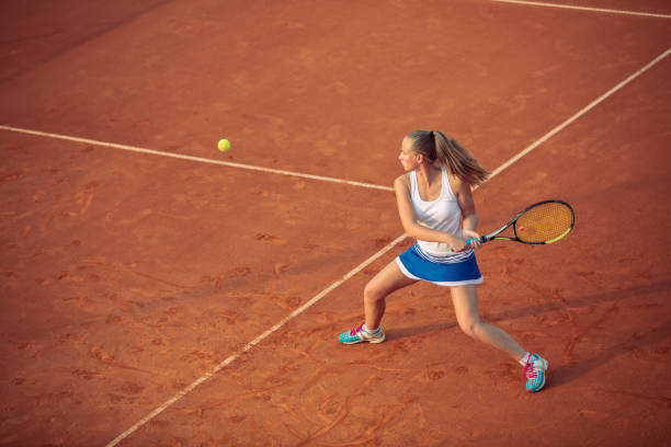 mujer jugando al tenis en pista de arcilla, con un atuendo deportivo y un estilo de vida saludable - tennis serving sport athlete fotografías e imágenes de stock