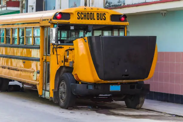 Old yellow schoolbus with open bonnet on the street of Havana, Cuba
