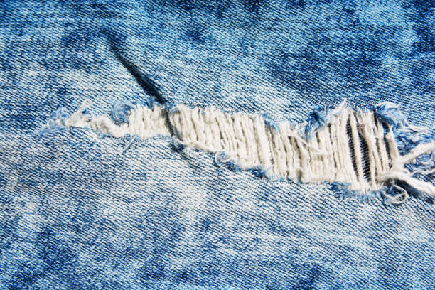 istock Denim texture.Blue jeans with threads and holes for the background 1155545889