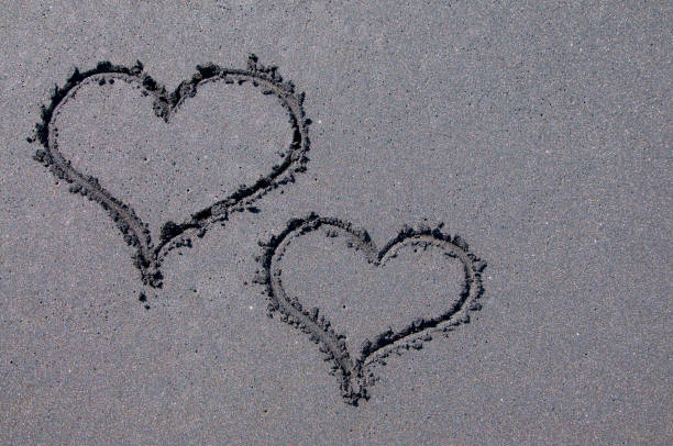 kształty serca na czarnej piaszczystej plaży - beach love heart shape two objects zdjęcia i obrazy z banku zdjęć