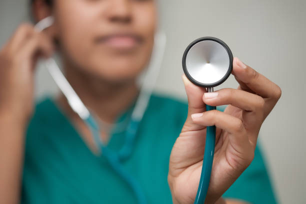 A female healthcare professional taking a reading using a stethoscope and carefully listening to form a diagnosis. stock photo