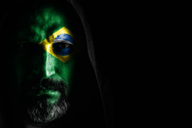 Brutal man with a gray beard in the hood with sharp shadows on a black background. Copy space.