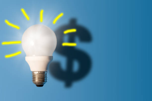 istock Light bulb on bright blue background with a dollar sign shadow. Conception good idea it's money. 1155556094