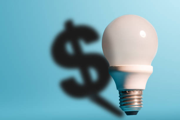 istock Light bulb on bright blue background with a dollar sign shadow. Conception good idea it's money. 1155556148
