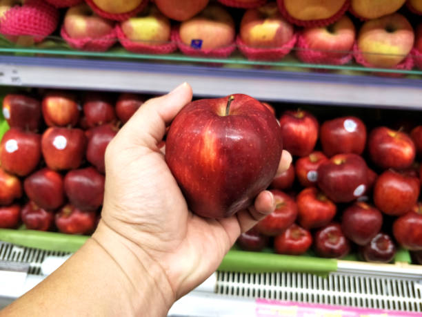 istock Man hand choosing red apple in the supermarket. 1155559884