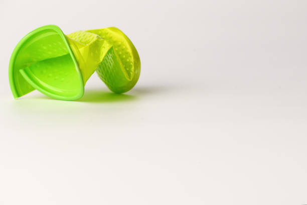 Green disposable plastic Cup broken lies on white background. Isolated background. Cup with pimples.