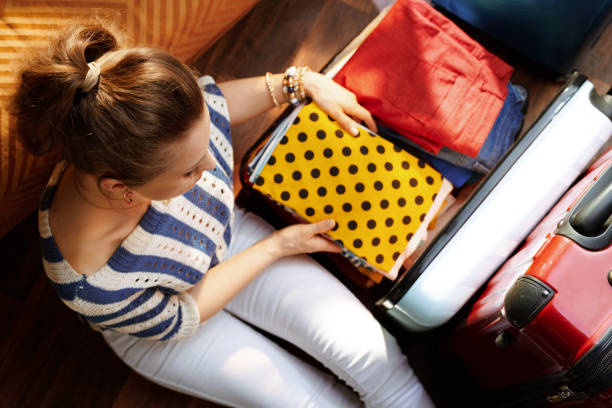 istock elegant woman putting stuff in open travel suitcase 1155564255