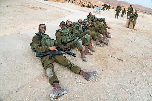 Masada, Israel. 23 October 2018: Israeli male soldiers resting on the ground after military exercises on Masada fortress territory