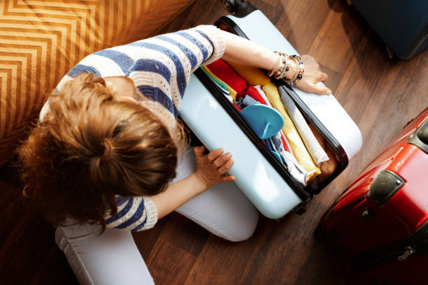 istock stylish woman closing over packed suitcase 1155567485