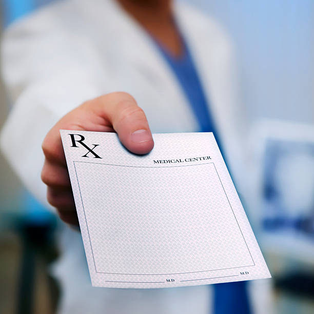 Doctor's Hand holding Prescription Pad Doctor holding an medical Rx out to the camera. Square shot. prescription medicine stock pictures, royalty-free photos & images