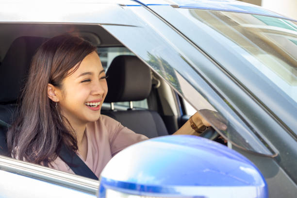 junge asiatische frau mit dem auto und befestigen den sicherheitsgurt mit freudigem positiven ausdruck während der fahrt auf die reise, entspannte lächeln glückliche frau auf road trip urlaubskonzept - wayfaring stock-fotos und bilder